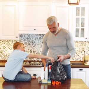 Grey haired dad with beard and small kid preparing cleaning stuff for tidying up kitchen