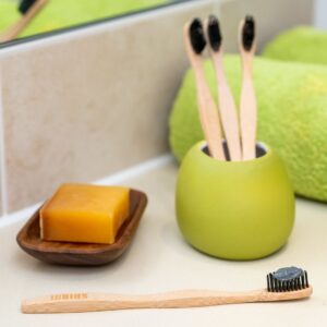 Sustainable bathroom setup with bamboo toothbrushes, soap, and a green towel.