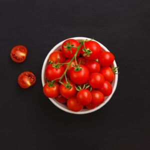 Top view of fresh red healthy tomatoes with green stems placed on black background