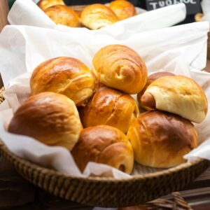 Freshly baked bread rolls are displayed in a basket.
