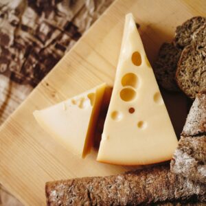 Close-up of cheese and rustic bread on a wooden board, ideal for culinary themes.