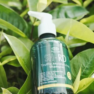 Truffle moisturizing shampoo bottle nestled among green leaves.