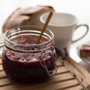 a jar of jam sitting on top of a wooden cutting board