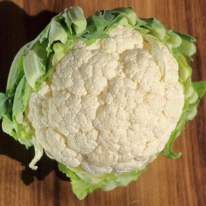 A fresh head of cauliflower on a wooden surface